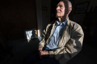 Pearl Harbor survivor and World War II Navy veteran David Russell, 101, poses for a photo along with a painting of the USS Oklahoma at his home on Monday, Nov. 22, 2021, in Albany, Ore. (AP Photo/Nathan Howard)