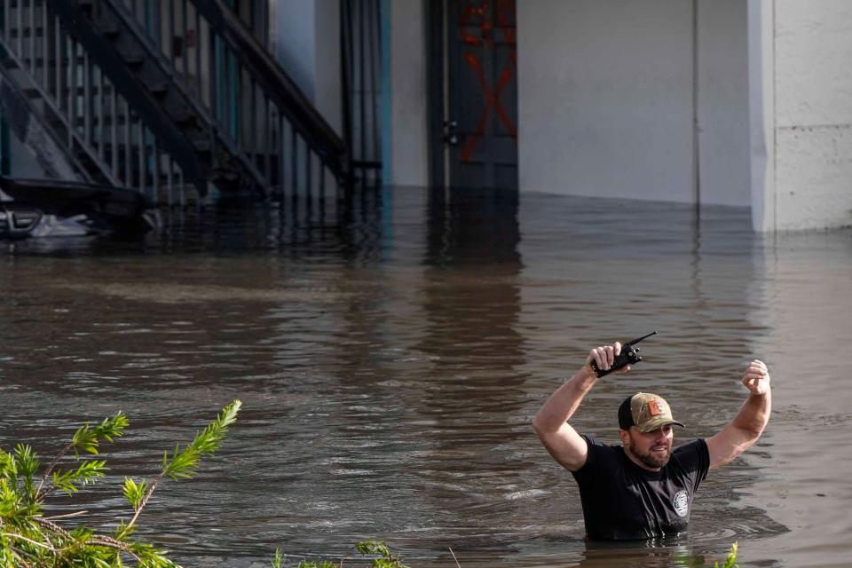 A water rescue team member walks through flood waters at an apartment complex in Clearwater, Florida, on Thursday. ((AP Photo/Mike Stewart))