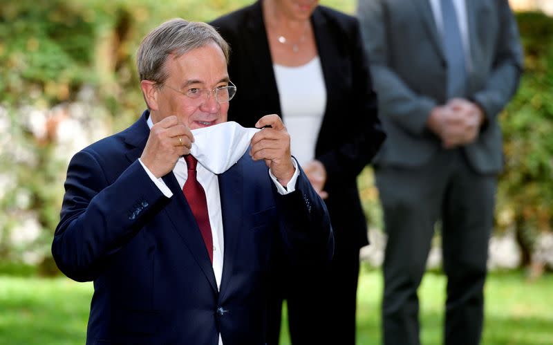 FILE PHOTO: North Rhine-Westphalia's State Premier Armin Laschet takes off his face mask as he arrives for a family photo prior to a North Rhine-Westphalian cabinet meeting in Duesseldorf