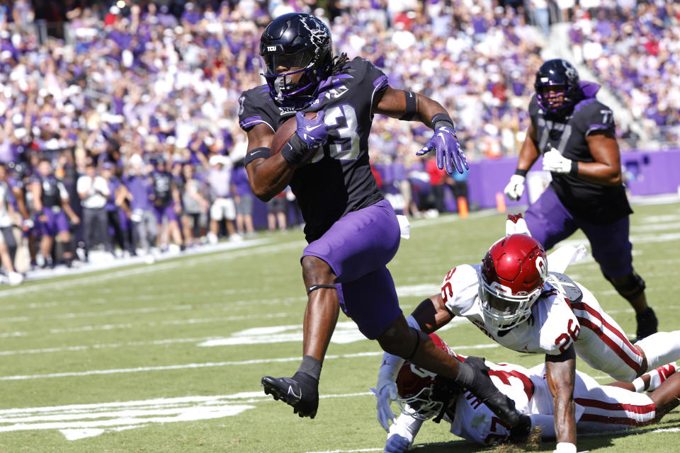 TCU running back Kendre Miller (33) escapes the grasp of Oklahoma defensive back Kani Walker (26) to score a touchdown during the first half of an NCAA college football game Saturday, Oct. 1, 2022, in Fort Worth, Texas. (AP Photo/Ron Jenkins)