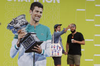 Fans take a selfie with a photo of defending champion Novak Djokovic of Serbia ahead of first round matches at the Australian Open tennis championships in Melbourne, Australia, Monday, Jan. 17, 2022. Djokovic was deported from Australia Sunday, Jan 16, after losing a bid to stay in the country to defend his Australian Open title despite not being vaccinated against COVID-19. (AP Photo/Hamish Blair)