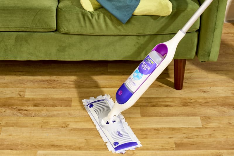 angled shot of a white swiffer power mop being used on a hardwood floor.