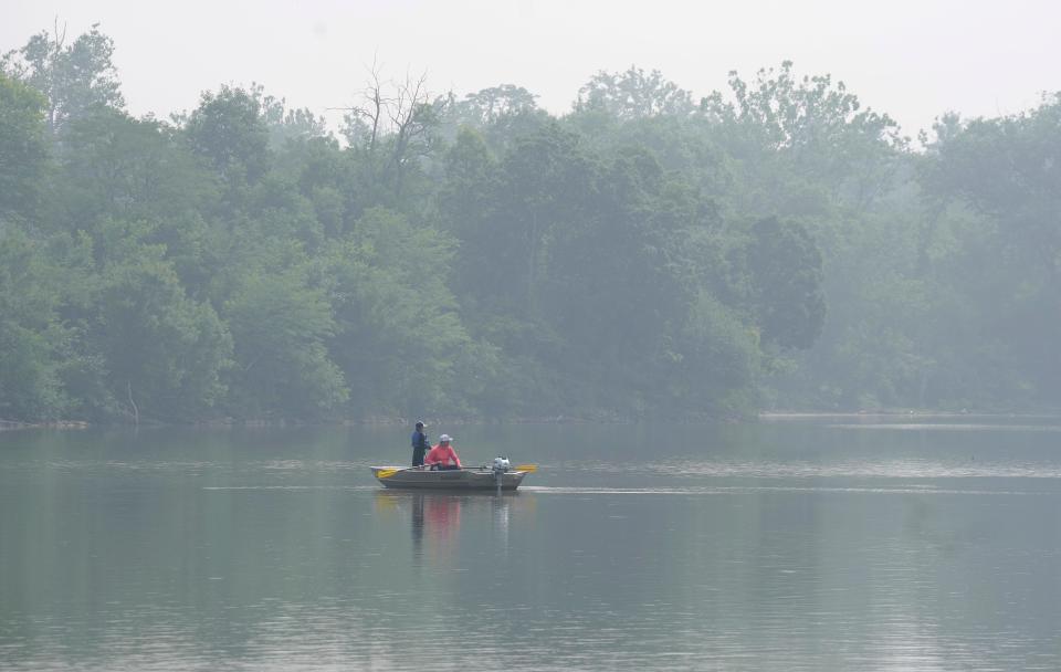 Haze surrounds Winton Woods Lake as people fish at Winton Woods Park in 2023.