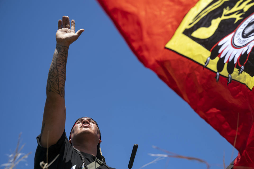 Roy Broncheau, aka Walks Through Hail, raises his hand to the sky after performing a prayer with tobacco on the bank of the Mississippi River, on Monday, June 7, 2021, in Clearwater County, Minn. More than 2,000 Indigenous leaders and "water protectors" gathered in Clearwater County from around the country to protest the construction of Enbridge Line 3. The day started with a prayer circle and moved on to a march to the Mississippi headwaters where the oil pipeline is proposed to be built. (Alex Kormann/Star Tribune via AP)