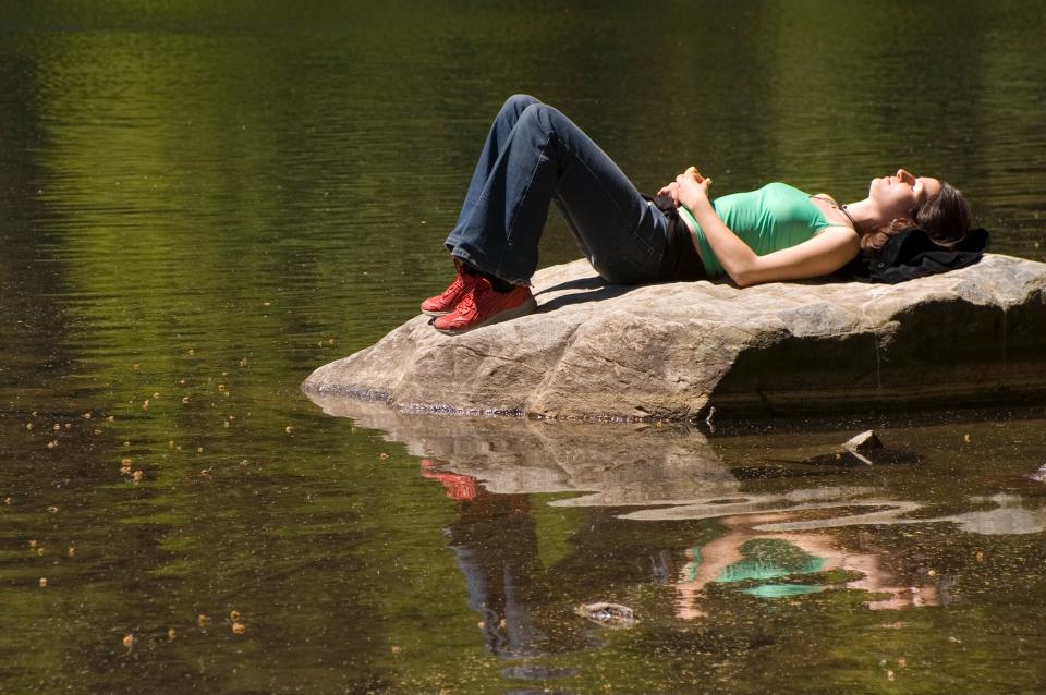 (GERMANY OUT) Junge Frau beim Sonnenbaden auf einem Felsen an einem See, woman lying on a rock at the lake (Photo by Wodicka/ullstein bild via Getty Images)