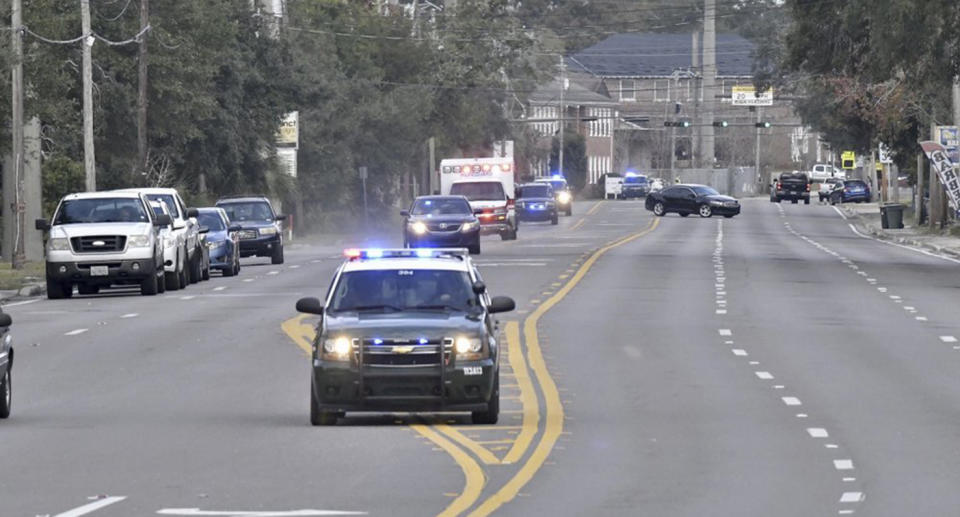 Police escort an ambulance to the base where a shooter opened fire in a classroom