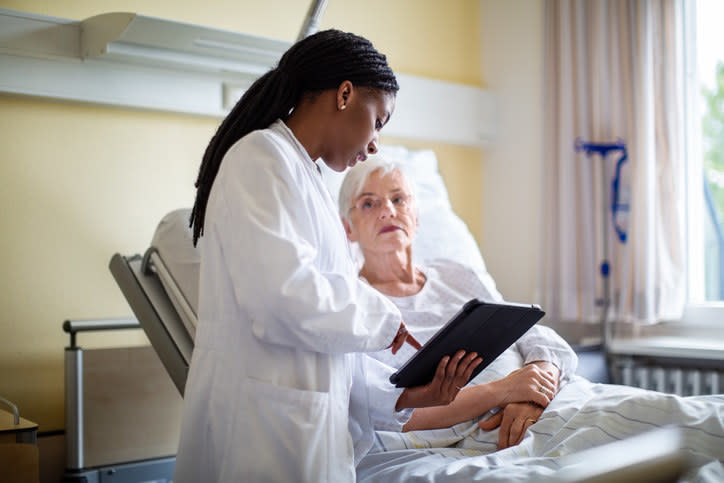 A doctor showing a patient something on an iPad.