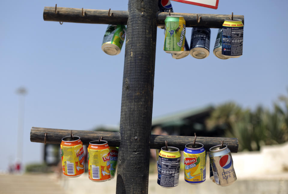 FILE - Empty soft drink cans hung in a post to be used as ashtrays at Carcavelos beach in Cascais, near Lisbon, Wednesday, Aug. 28, 2013. Global supermarket chain Carrefour will stop selling PepsiCo products in its stores in France, Belgium, Spain and Italy over price increases for popular items like Lay's potato chips, Quaker Oats, Lipton tea and its namesake soda. (AP Photo/Francisco Seco, File)