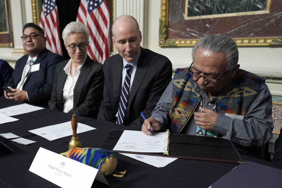 Chair Gerry Lewis of the Yakama Nation, right, signs a document during a signing ceremony in Washington, Friday, Feb. 23, 2024. The agreement is between the Biden administration and state and Tribal governments in the Pacific Northwest to restore wild salmon populations, expand Tribally sponsored clean energy production, and provide stability for communities that depend on the Columbia River System for agriculture, energy, recreation, and transportation. (AP Photo/Susan Walsh)