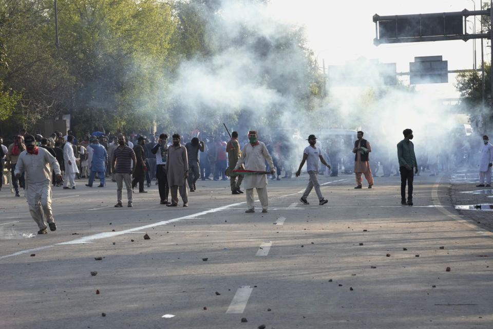 Supporters of Pakistan's former Prime Minister Imran Khan run for cover as police fire tear gas shells to disperse them during clashes, in Lahore, Pakistan, Wednesday, March 8, 2023. Pakistani police used water cannons and fired tear gas to disperse supporters of the country's former Prime Minister Khan Wednesday in the eastern city of Lahore. Two dozen Khan supporters were arrested for defying a government ban on holding rallies, police said. (AP Photo/K.M. Chaudary)