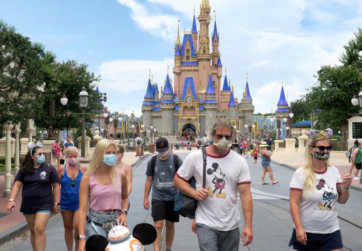 Guests wear masks as required to attend the official reopening day of the Magic Kingdom at Walt Disney World in Lake Buena Vista, Fla., Saturday, July 11, 2020. Disney reopened two Florida parks, the Magic Kingdom and Animal Kingdom, Saturday, with limited capacity and safety protocols in place in response to the coronavirus pandemic.