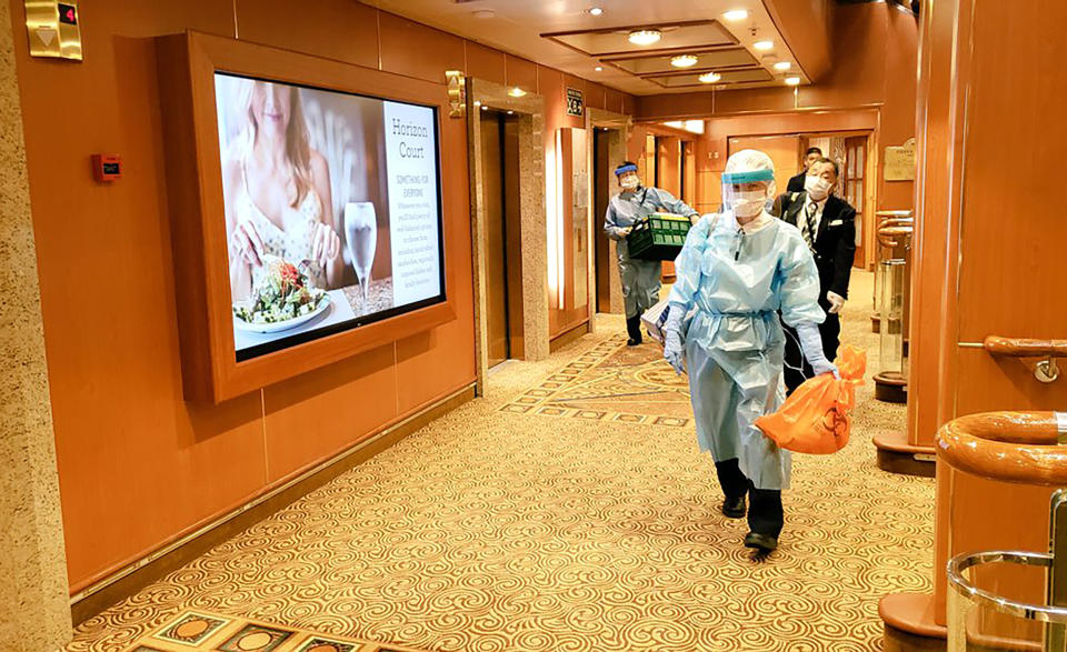 In this Tuesday, Feb. 4, 2020, photo taken by the passenger, medical workers in protective suits walk on the cruise ship Diamond Princess anchored off Yokohama, south of Tokyo. The 3,700 people on board faced a two-week quarantine in their cabins. Health workers said Thursday, Feb. 6, 2020, 10 more people from the Diamond Princess were confirmed sickened with the virus, in addition to 10 others who tested positive on Wednesday. The 10 were dropped off as the ship docks and transferred to nearby hospitals for further test and treatment. (@daxa_tw via AP)