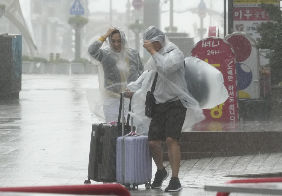 People struggle in the rain and wind as the tropical storm named Khanun approaches to the Korean Peninsular, in Busan, Thursday, Aug. 10, 2023. (AP Photo/Ahn Young-joon)