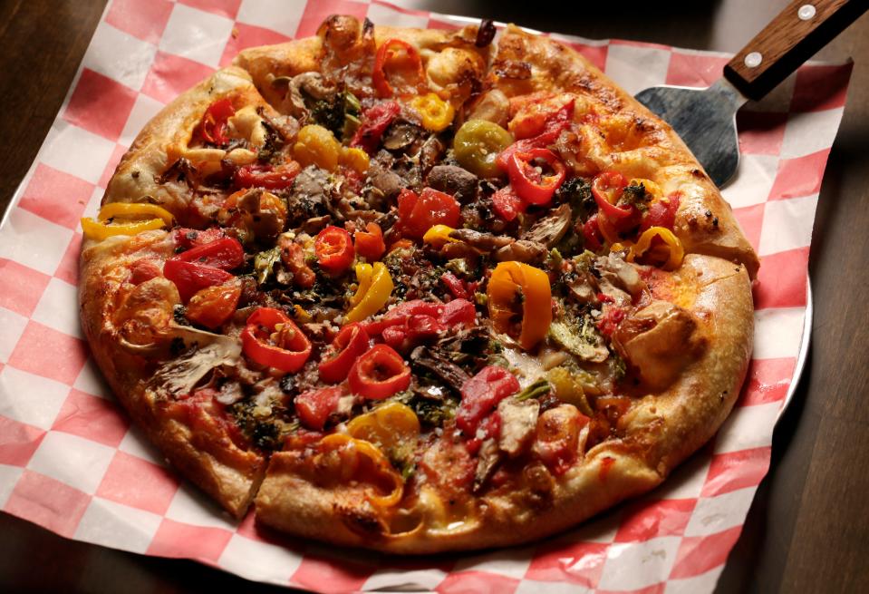 The Veg Out pizza at Wild Pie is made with house-made red sauce, dairy-free mozzarella and parmesan, roasted broccoli, mixed mushrooms, roasted red peppers, sweet peppers, caramelized onions, cherry tomatoes, and extra virgin olive oil.