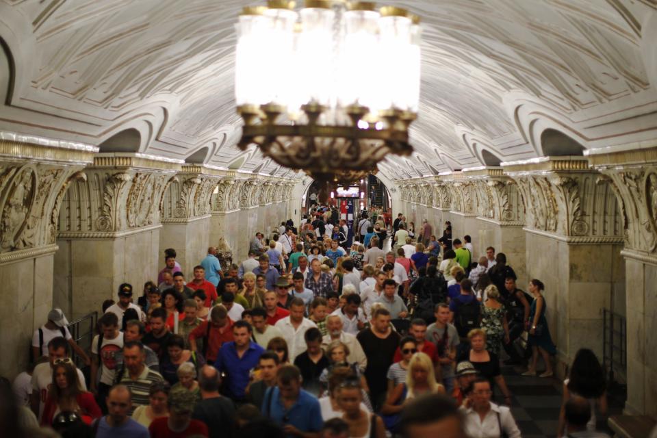 People walk through Prospekt Mira metro station in Moscow August 14, 2013. To step onto the Moscow metro is to step back in time and immerse yourself in a museum rich in architecture and history. Opened in 1935, it is an extravagant gallery of Communist design, featuring Soviet artworks, statues, chandeliers, stained glass and ceiling mosaics. Built under Stalin, the metro now transports 7 to 9 million people a day and costs 30 Rubles, around $1, for a single ride. Picture taken August 14, 2013. REUTERS/Lucy Nicholson (RUSSIA - Tags: TRANSPORT SOCIETY) ATTENTION EDITORS: PICTURE 02 OF 24 FOR PACKAGE 'RIDING THE MOSCOW METRO' SEARCH 'MOSCOW CHANDELIERS' FOR ALL IMAGES