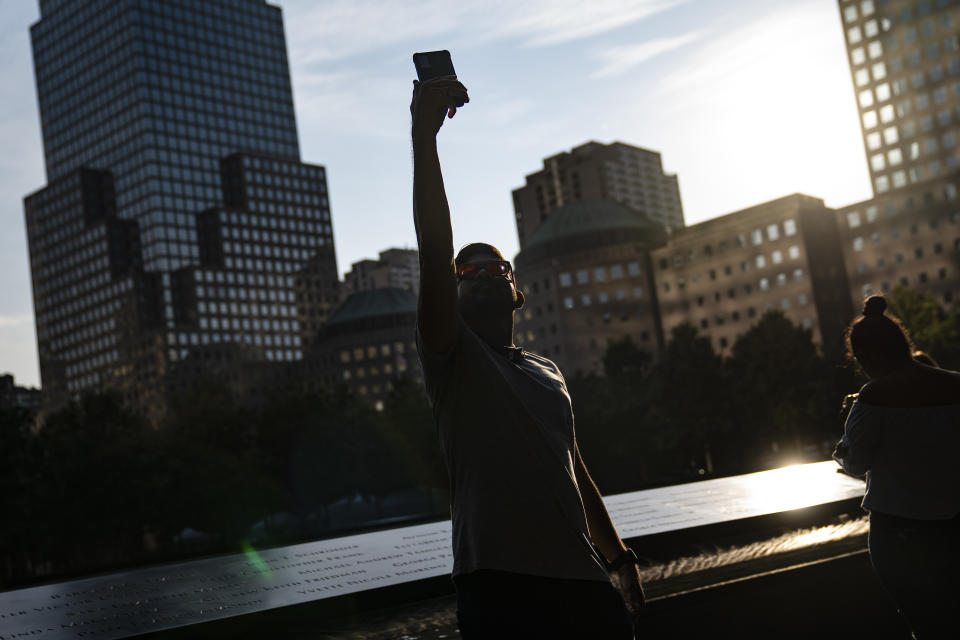 A visitor takes a selfie beside the north pool at the National September 11 Memorial & Museum, Wednesday, Sept. 8, 2021, in New York. (AP Photo/John Minchillo)