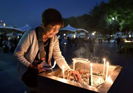 A woman lights up a candle in front of the cenotaph for the victims of the 1945 atomic bombing at Peace Memorial Park in Hiroshima, western Japan, in this photo taken by Kyodo August 6, 2016. Mandatory credit Kyodo/via REUTERS