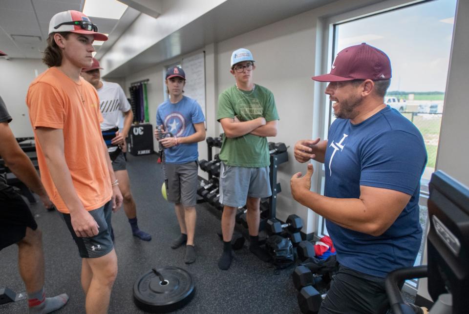 Head coach Chris Lyle, right, instructs his players as the baseball team works out at L.E.A.D. Academy in Pace on Monday, July 11, 2022.