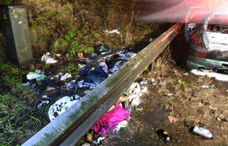 Tattered clothes and bottles lay strewn on the ground next to the destroyed vehicle (PA)