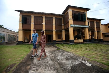 Tourists walk away holding hands after visiting the Da-Silva slave museum in Porto-Novo