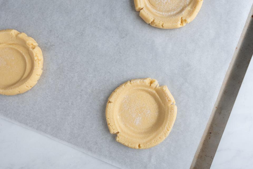 Sugar cookie rounds on parchment paper with smaller circle indent in each round