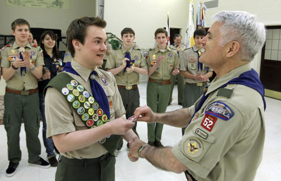 FILE - In this Feb. 10, 2014 fie photo Pascal Tessier, left, a gay Boy Scout, receives his Eagle Scout badge from Troop 52 Scoutmaster Don Beckham, right, in Chevy Chase, Md., to become one of the first openly gay scouts to reach scouting's highest rank. The Boy Scouts of America said Wednesday, Feb. 12, 2014 that it lost 6 percent of its membership after an often-bruising year in which it announced it would accept openly gay boys for the first time, over the objections of some participants who eventually left the organization. (AP Photo/Luis M. Alvarez, File)