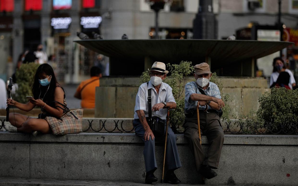 Residents of Madrid wear face masks as they sit by a fountain in the Spanish capital on Wednesday - Anadolu