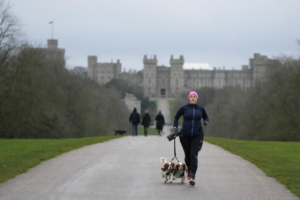 A jogger and her two dogs on the Long Walk at Windsor, England, on Christmas Day, Saturday, Dec. 25, 2021. Britain's Queen Elizabeth II has stayed at Windsor Castle instead of spending Christmas at her Sandringham estate due to the ongoing COVID-19 pandemic. (AP Photo/Alastair Grant)