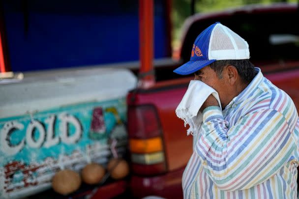 PHOTO: Andres Matamoros wipes the sweat from his face while selling fresh fruit and cold coconuts from his roadside stand, June 28, 2023, in Houston, during a stretch of scorching temperatures. (David J. Phillip/AP)