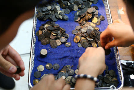 Officers count coins that were removed from the stomach of Omsin, a 25 year old femal green sea turtle, after a surgical operation at the Faculty of Veterinary Science, Chulalongkorn University in Bangkok, Thailand March 6, 2017. REUTERS/Athit Perawongmetha