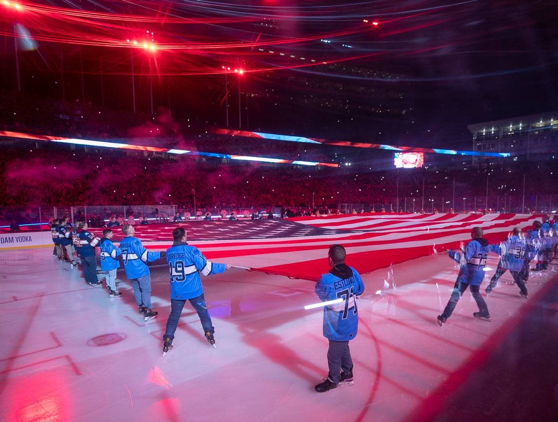 A large America flag covers the ice during the National Anthem prior to the Stadium Series game on Saturday, February 18, 2022 at Carter-Finley Stadium in Raleigh, N.C.