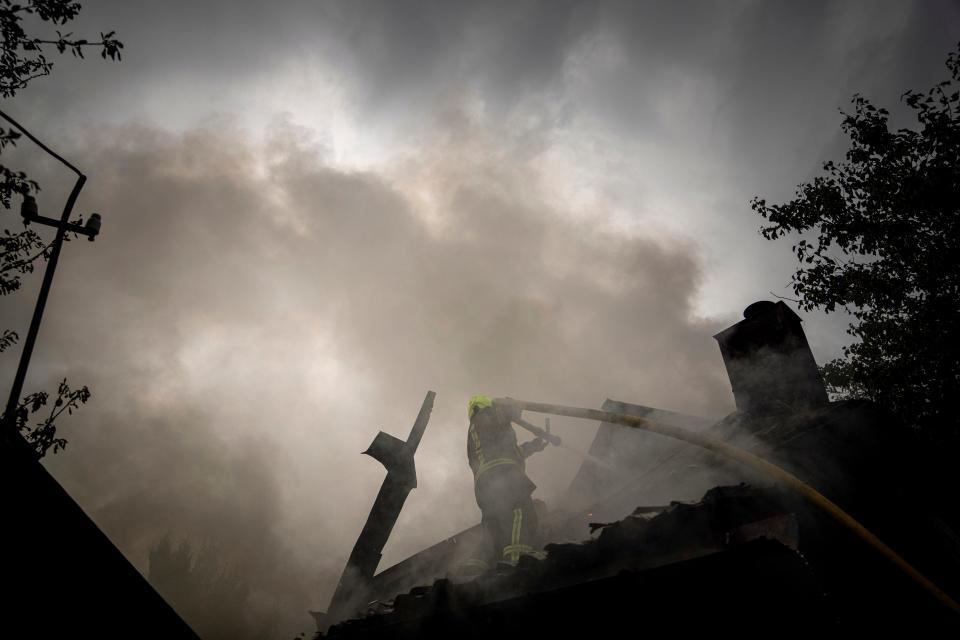 A rescue worker puts out the fire on a destroyed house after a Russian attack in a residential neighborhood in downtown Kharkiv, Ukraine, on July 11, 2022.  The top official in the Kharkiv region said Monday the Russian forces launched three missile strikes on the city targeting a school, a residential building and warehouse facilities.