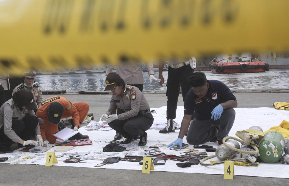 Police officers inspect personal belongings of passengers that have been recovered. Image: AP