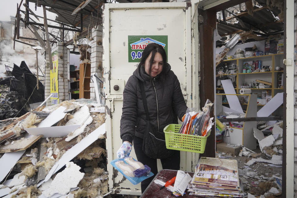 A vendor collects surviving goods from her shop damaged by Russian rocket attack in Kharkiv, Ukraine, Tuesday, Jan. 23, 2024. (AP Photo/Andrii Marienko)