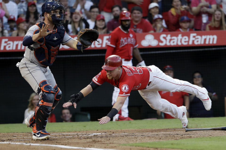 Los Angeles Angels' Kole Calhoun, right, scores past Houston Astros catcher Max Stassi on a three-run double by Albert Pujols during the first inning of a baseball game Tuesday, July 16, 2019, in Anaheim, Calif. (AP Photo/Marcio Jose Sanchez)