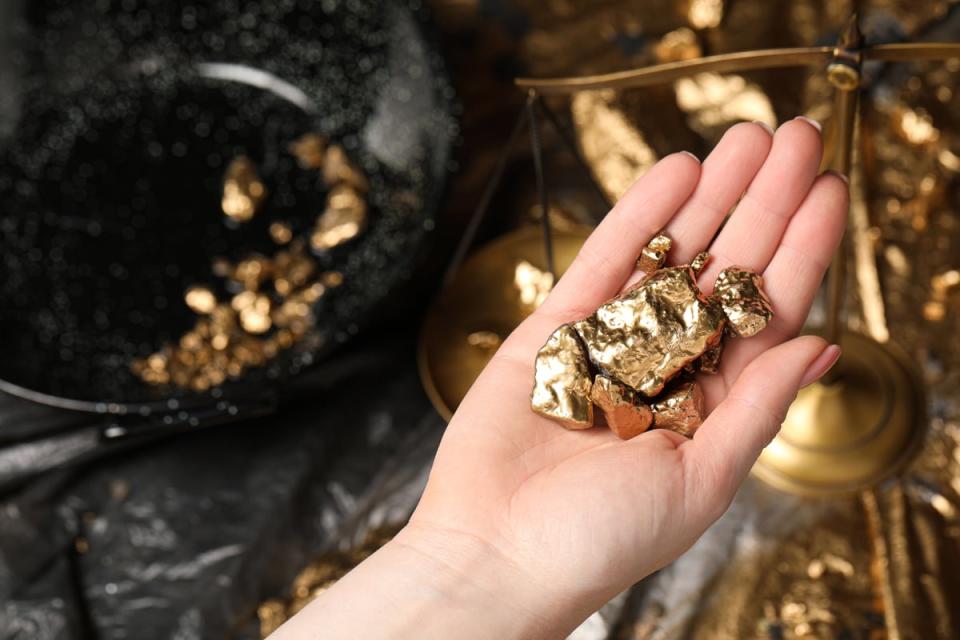 A person holds gold nuggets in their hand. 