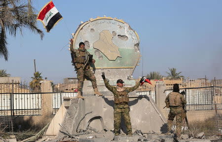 A member of the Iraqi security forces holds an Iraqi flag at a government complex in the city of Ramadi, December 28, 2015. REUTERS/Stringer