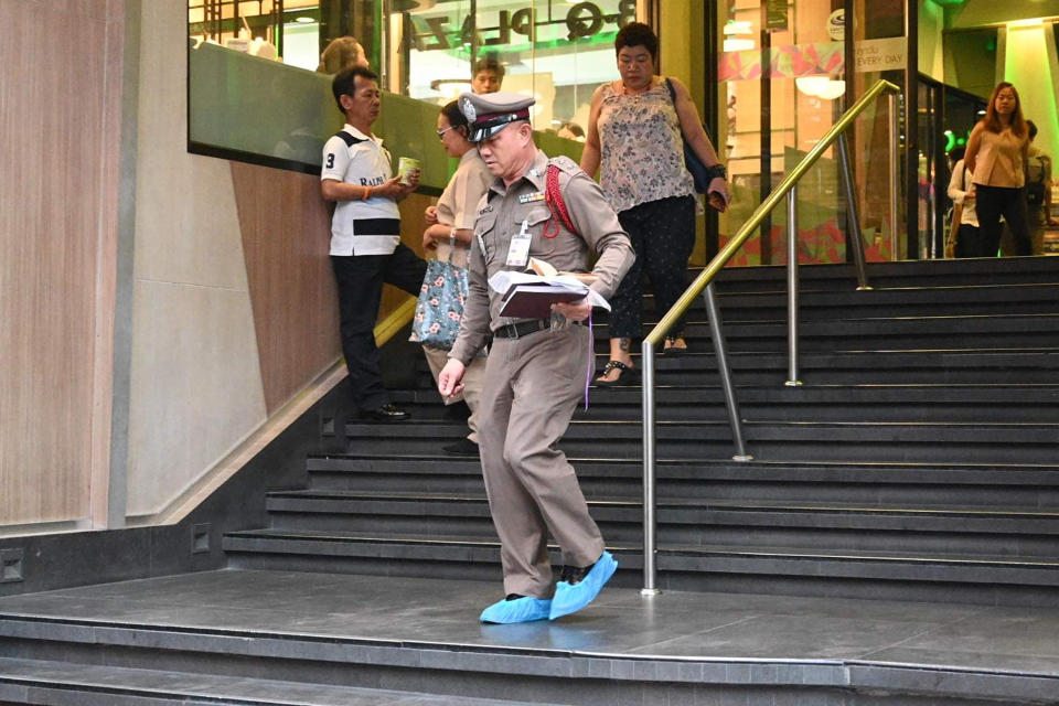 A member of the Thai Royal Police walk out of the Century Plaza mall Tuesday, Feb. 18, 2020 in Bangkok, Thailand. Gun violence has struck again at a shopping mall in Thailand, where a man in the nation's capital Bangkok shot dead one woman working in a beauty clinic and wounded another. (AP Photo)