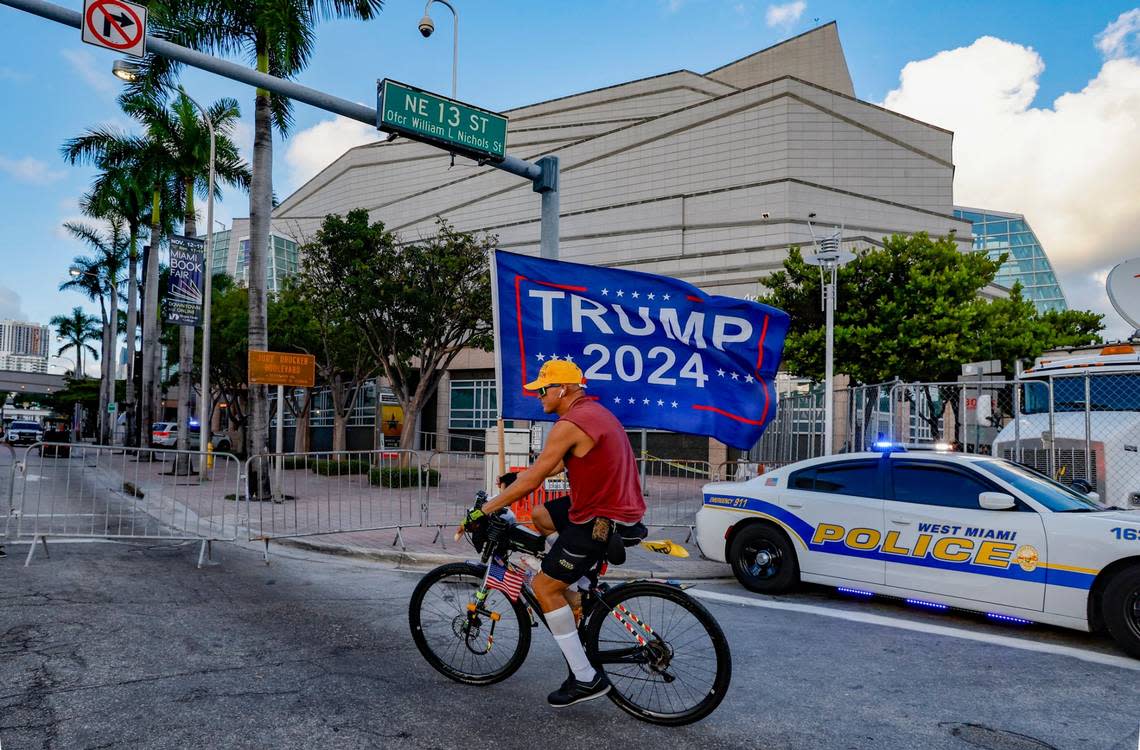 Former President Donald Trump supporter, Chaunce O’Connor, 41 of Miami, carries a flag as he rides past the Adrienne Arsht Center for the Performing Arts of Miami-Dade County just hours before the start of the third Republican presidential primary debate on Wednesday, November 8, 2023, in downtown Miami, Fla. Al Diaz/adiaz@miamiherald.com