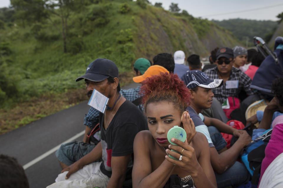 In this Nov. 2, 2018 photo, Honduran transgender Alexa Amaya, who is part of a group of 50 or so LGBTQ migrants traveling with the migrant caravan hoping to reach the U.S. border, uses a compact mirror to apply makeup while riding in the back of a flatbed truck to Sayula, Mexico. "I know it will be difficult to win asylum," said Alexa, a 24-year-old from Copan Honduras, "but we have to make the attempt." (AP Photo/Rodrigo Abd)