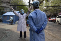 A health worker gestures as he chats with another in Wuhan in central China's Hubei province on Friday, April 3, 2020. Sidewalk vendors wearing face masks and gloves sold pork, tomatoes, carrots and other vegetables to shoppers Friday in the Chinese city where the coronavirus pandemic began as workers prepared for a national memorial this weekend for health workers and others who died in the outbreak. (AP Photo/Ng Han Guan)