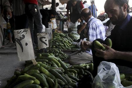 A man buys cucumbers at a souk in Aleppo, August 31, 2013. REUTERS/Muzaffar Salman