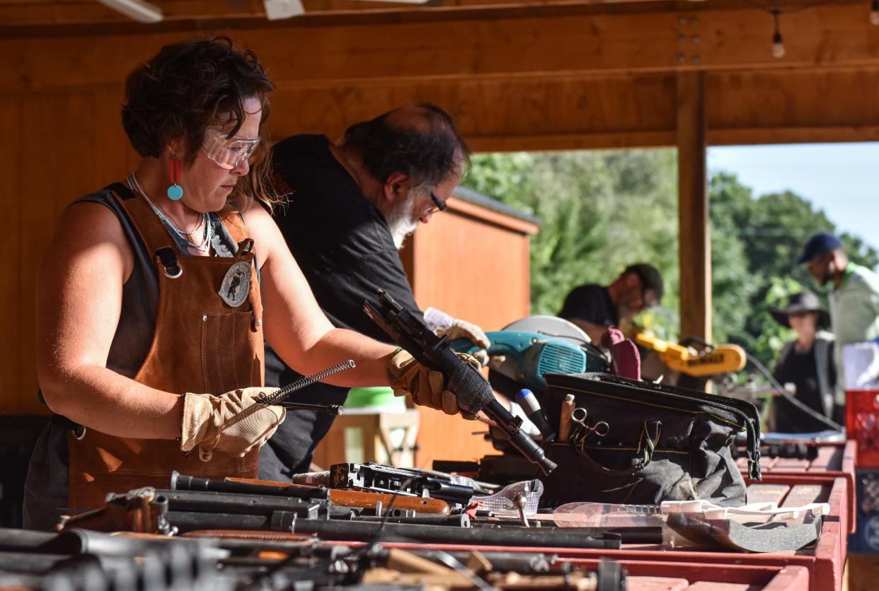 Dianna Oestreich and Steve Ritchey work to saw apart guns donated by the Akron Police Department at Akron Cooperative Farms, Thursday, July 18, 2024. The gun parts will be recycled and turned into gardening tools.