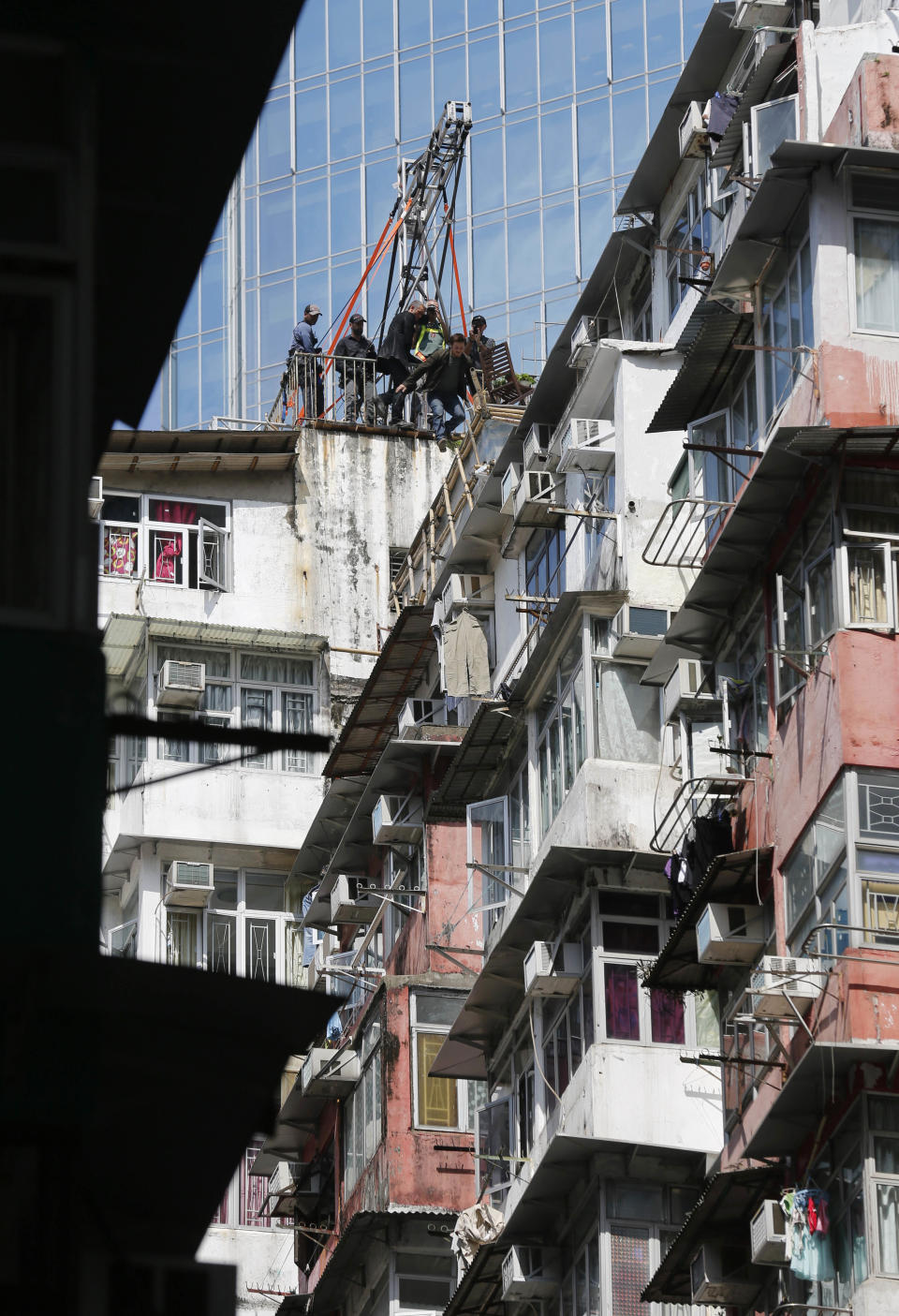 An actor jumps onto the roof of an old residential building during the filming of a scene for their latest movie "Transformers 4: Age of Extinction" in Hong Kong Friday, Oct. 18, 2013. Hollywood director Michael Bay, not shown in the photo, was attacked on Thursday and slightly injured on the set of the fourth installment of the "Transformers" movie series filming in Hong Kong, police said. The spokeswoman said Bay suffered a minor injury to his face but declined medical treatment. (AP Photo/Kin Cheung)