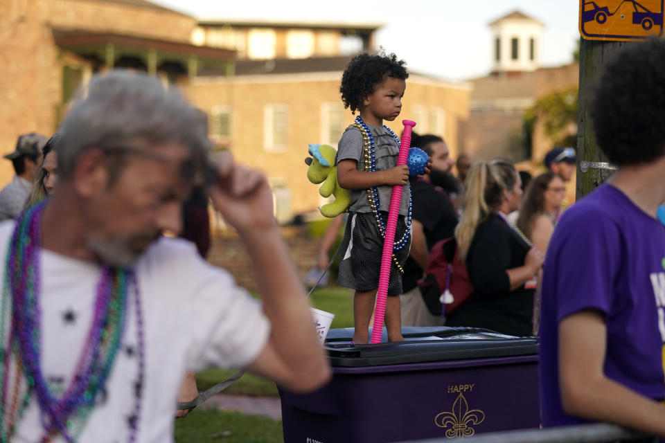 Xeavier Domingue, 2, stands on a trash can to catch throws during a parade dubbed "Tardy Gras," to compensate for a cancelled Mardi Gras due to the COVID-19 pandemic, in Mobile, Ala., Friday, May 21, 2021. (AP Photo/Gerald Herbert)