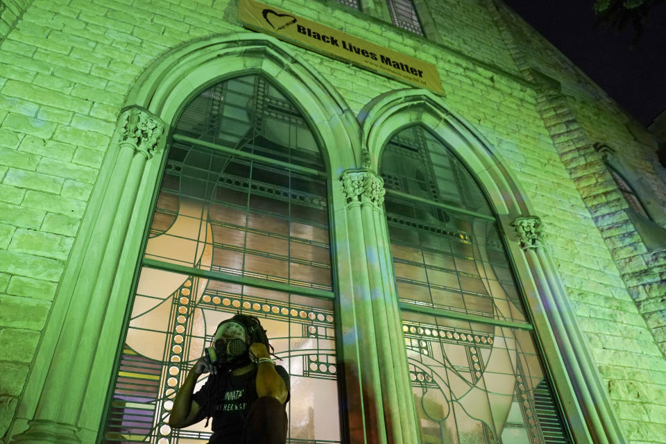 A protester wears a gas mask outside The First Unitarian church, Thursday, Sept. 24, 2020, in Louisville, Ky. Authorities pleaded for calm while activists vowed to fight on Thursday in Kentucky's largest city, where a gunman wounded two police officers during anguished protests following the decision not to charge officers for killing Breonna Taylor. (AP Photo/John Minchillo)