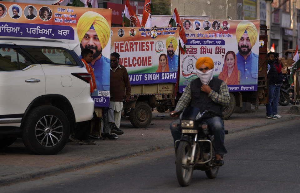 A motorcyclist drives past parked congress party election vehicles in Amritsar, in Indian state of Punjab, Tuesday, Feb. 15, 2022. India's Punjab state will cast ballots on Sunday that will reflect whether Indian Prime Minister narendra Modi's ruling Bharatiya Janata Party has been able to neutralize the resentment of Sikh farmers by repealing the contentious farm laws that led to year-long protests. (AP Photo/Manish Swarup)