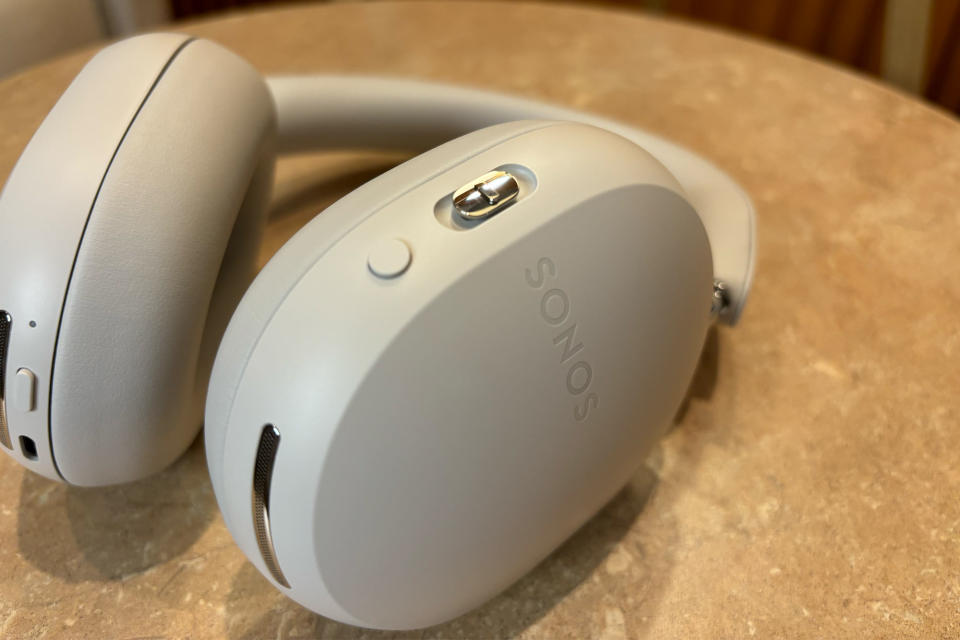 <p>White headphones laying flat on a small table, showing the buttons on both sides.</p>
