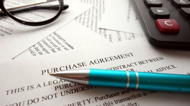 A pen sits on top of a purchase agreement. 