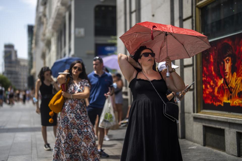 FILE - A woman holds an umbrella to shelter from the sun during a hot sunny day in Madrid, Spain, July 18, 2022. Looking back at 2022’s weather with months of analysis, the World Meteorological Organization says last year really was as bad as it seemed. (AP Photo/Manu Fernandez, File)